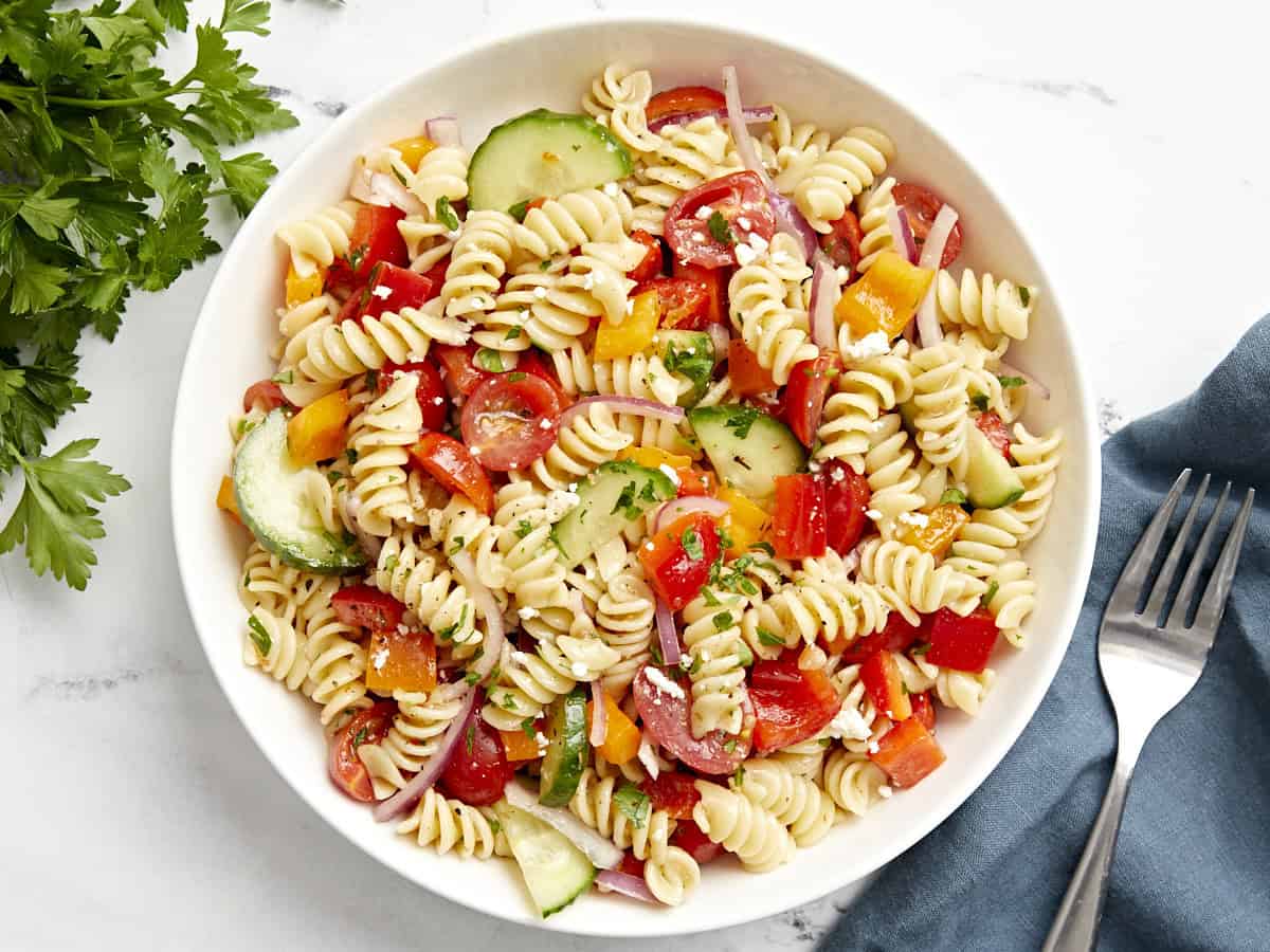 Overhead view of a serving of pasta salad on a plate with a fork on the side.