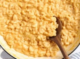 Overhead view of a pot of mac and cheese with a wooden spoon.