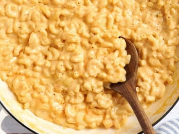 Overhead view of a pot of mac and cheese with a wooden spoon.