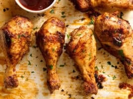 Overhead view of baked chicken drumsticks on a baking sheet.