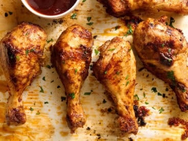 Overhead view of baked chicken drumsticks on a baking sheet.