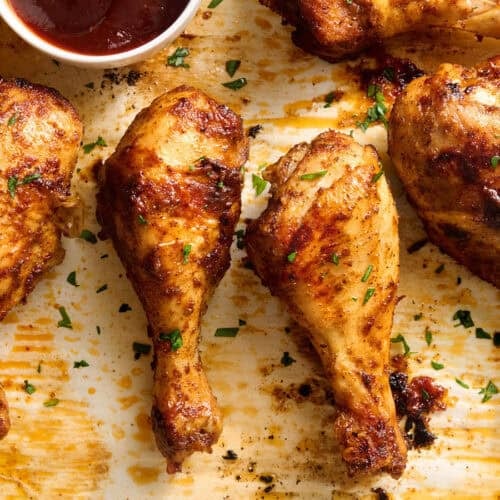 Overhead view of baked chicken drumsticks on a baking sheet.