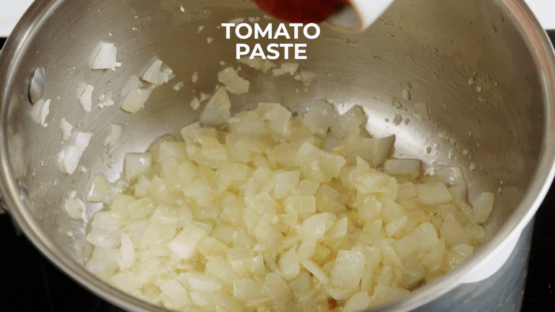 a diced onion being cooked and mixed with tomato paste