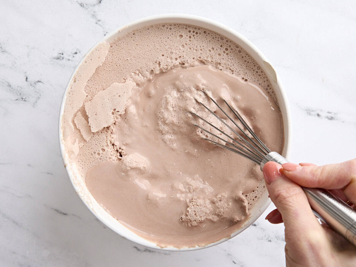 A whisk mixing a homemade frosty in a bowl.