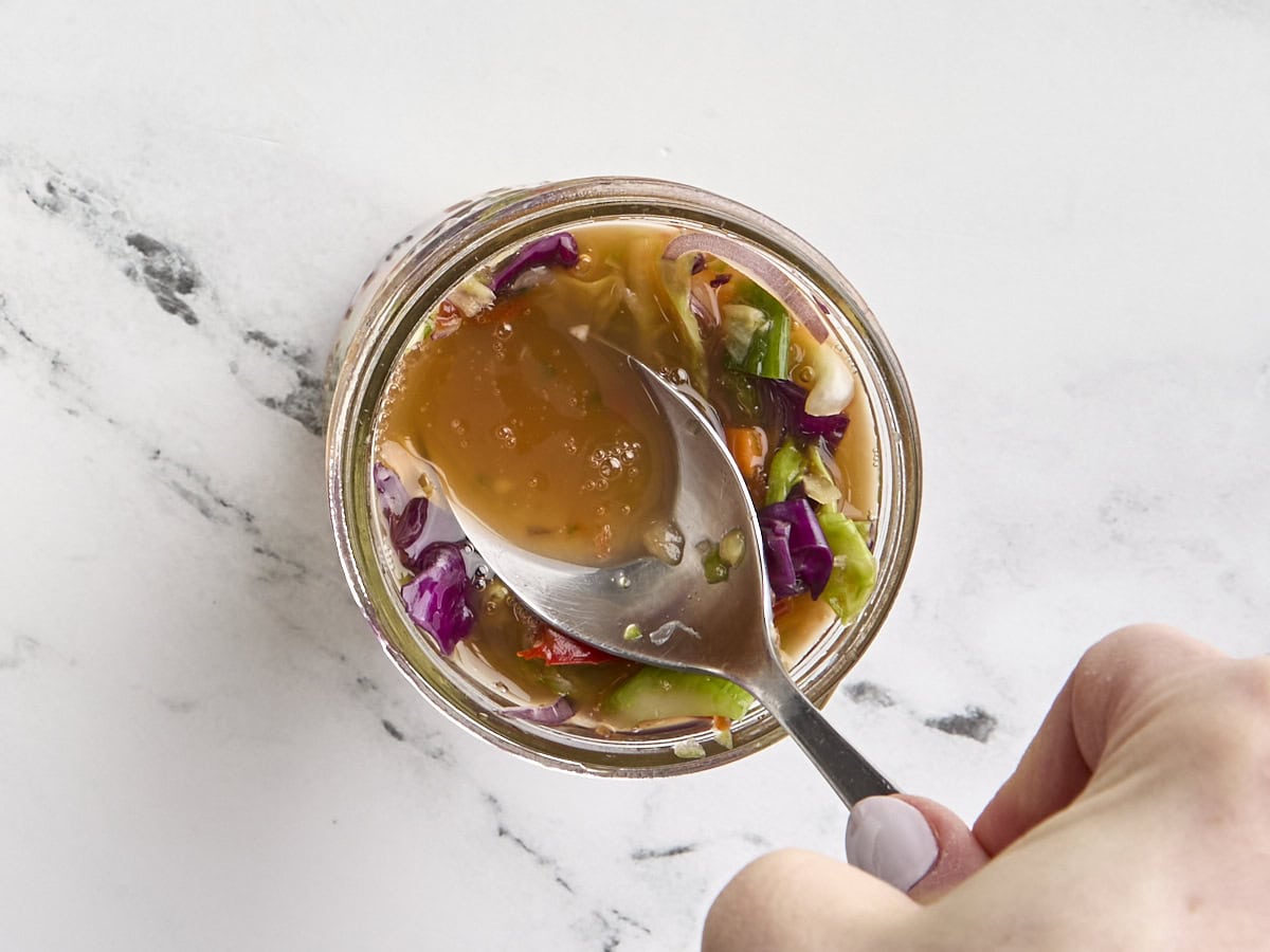 Extra vegetable brine being added to a jar of homemade kimchi.