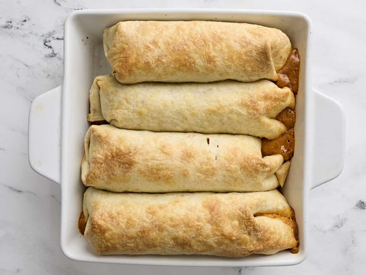 Finished baked chicken chimichangas in a baking dish.