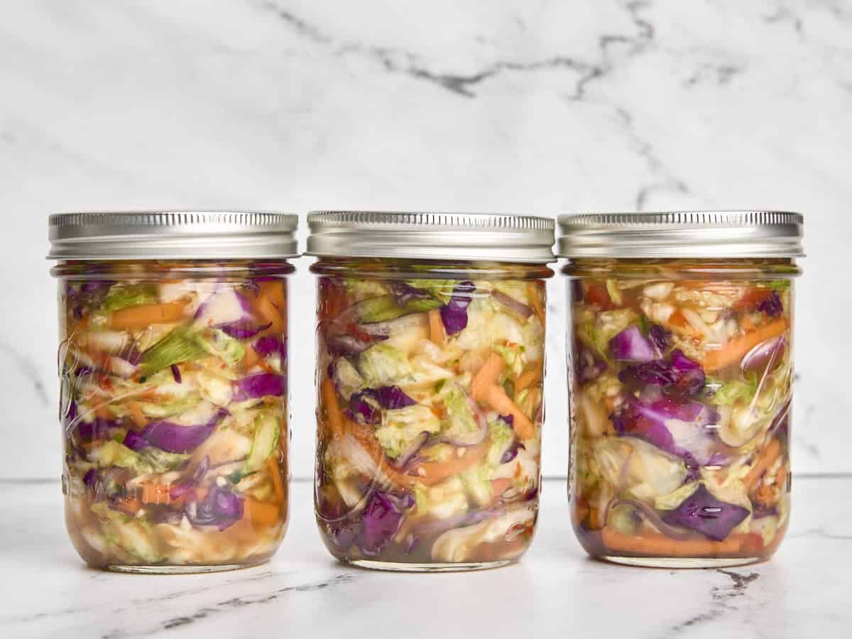 Lids added to three jars of homemade kimchi.