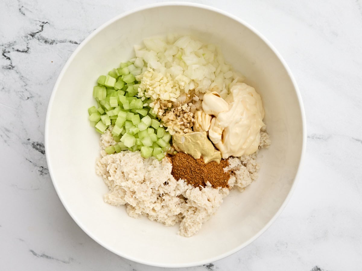 Diced onion, celery, garlic, seasonings mayonnaise, and canned crab meat in a mixing bowl.