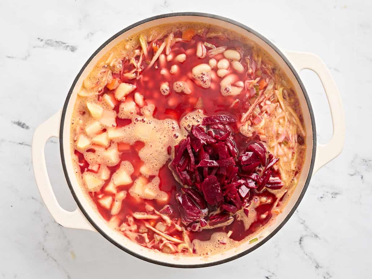 Potatoes and sliced beets added to a pot of homemade borscht.