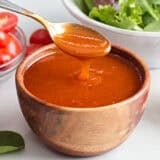 Side view of a bowl of french dressing, with a spoon taking some.