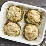 Overhead view of four philly cheesesteak stuffed peppers on a baking sheet.