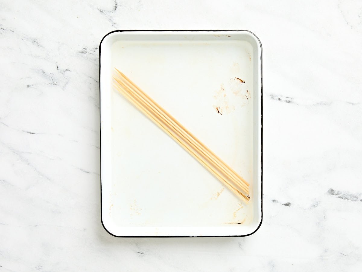 Wooden skewers in a dish of water.
