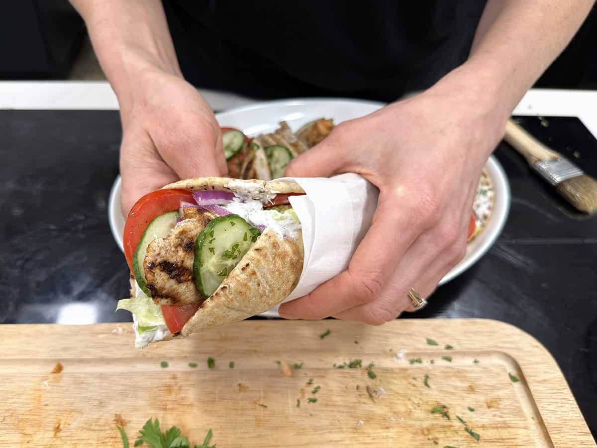 Hands holding a chicken shawarma wrap.