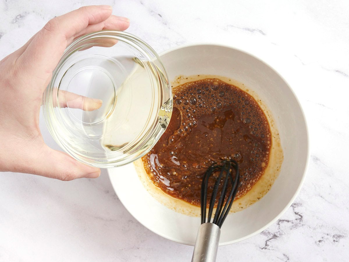 Oil being streamed into a homemade balsamic vinaigrette.