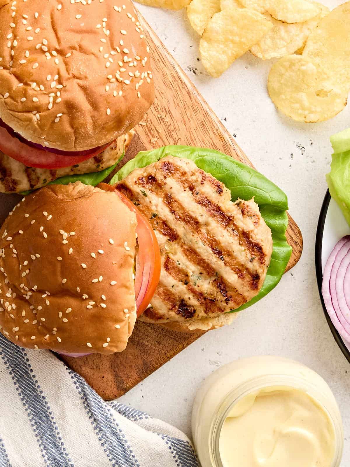 Overhead view of a homemade chicken burger on a wooden platter.