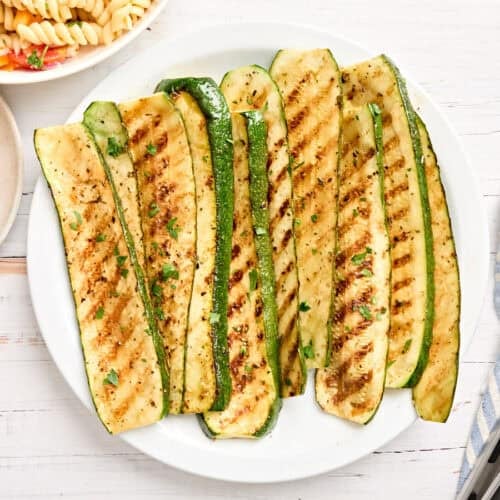 Overhead view of grilled zucchini slices on a plate.