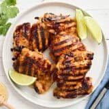 Overhead view of honey lime chicken on a plate with lime wedges.