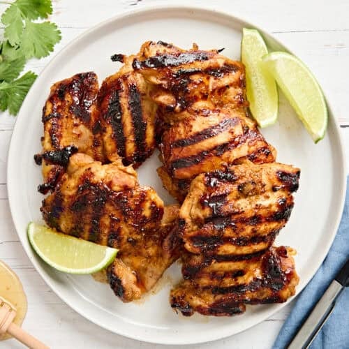 Overhead view of honey lime chicken on a plate with lime wedges.