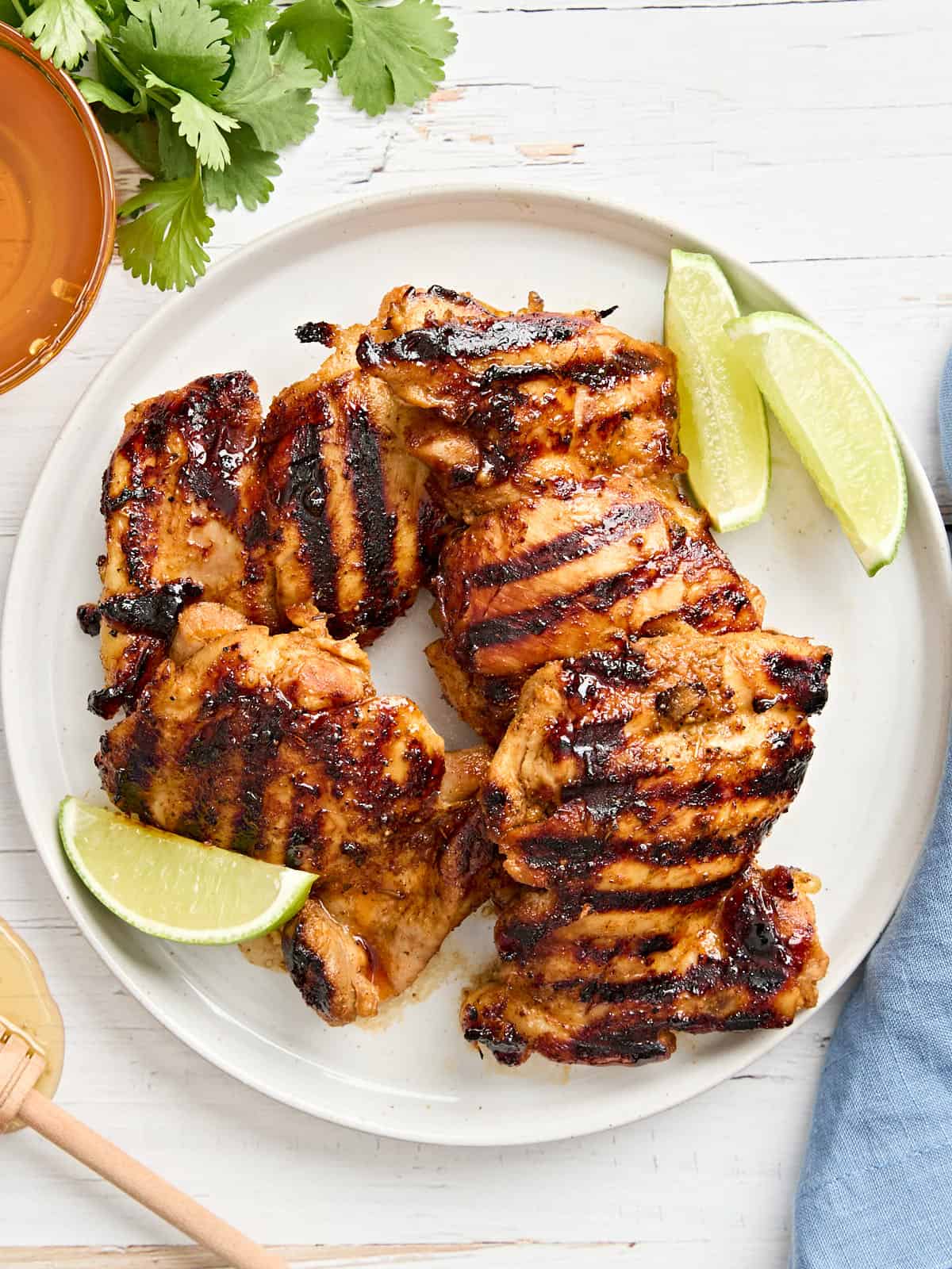 Overhead view of honey lime chicken on a plate with lime wedges.