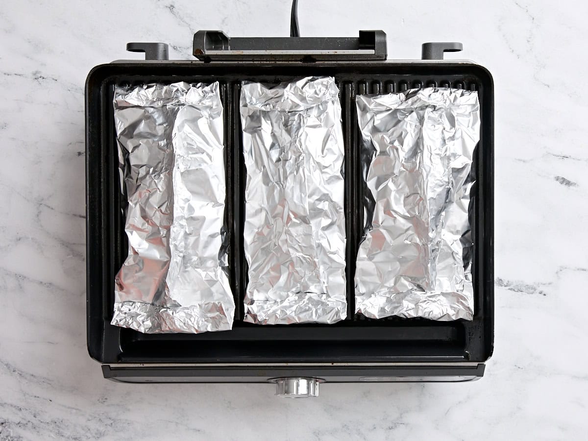 Shrimp and vegetable foil packets on a grill.
