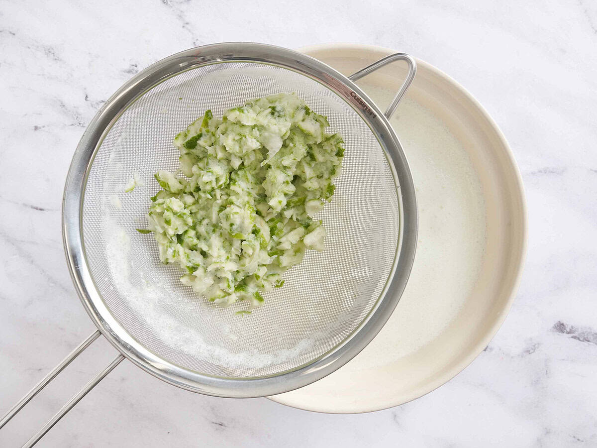 Lime pith in a strainer over a bowl of homemade brazil lemonade.