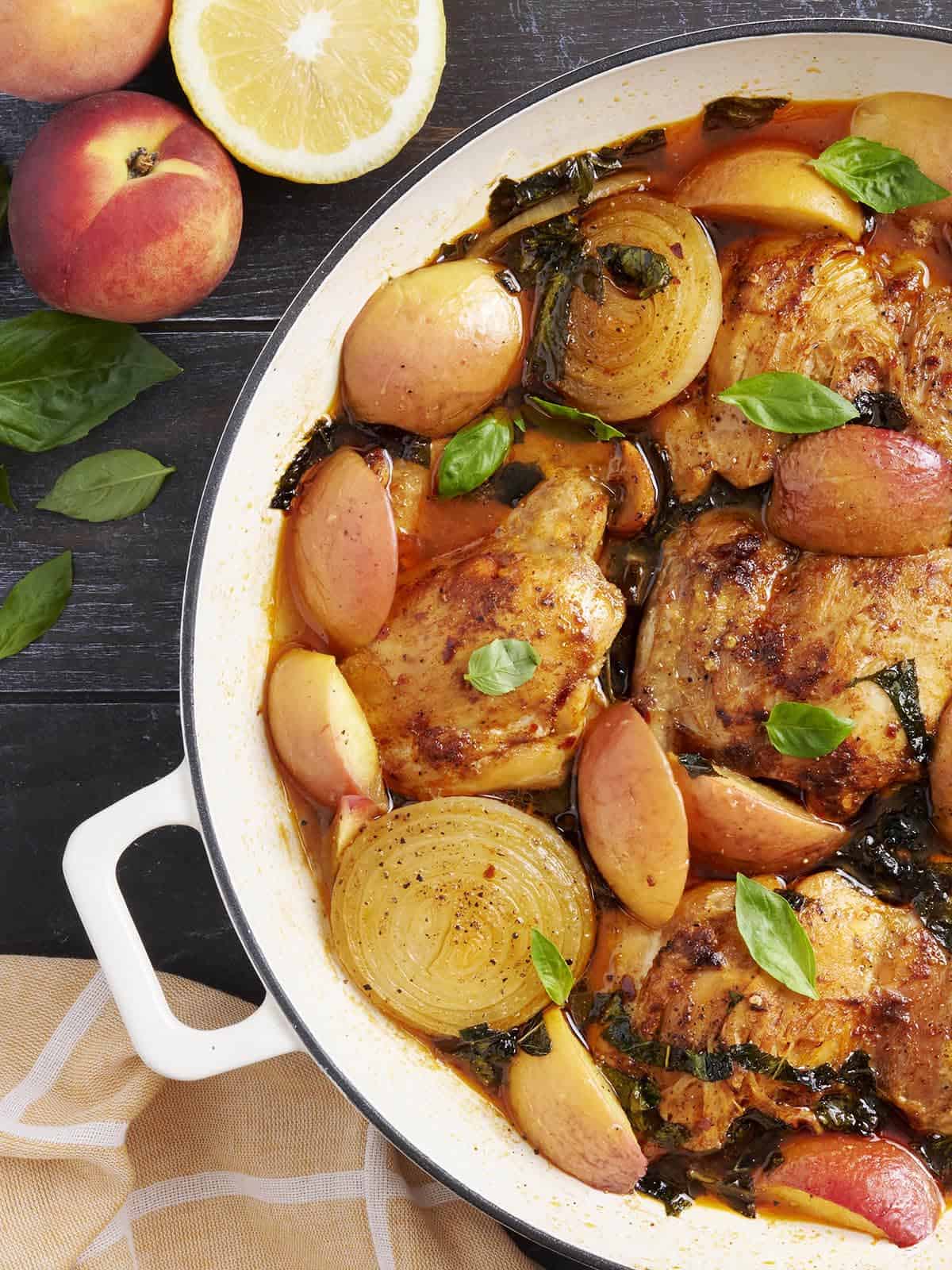 Overhead close up of braised chicken and peaches in a skillet.