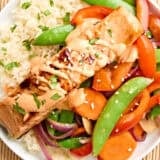 Overhead view of teriyaki salmon on a plate with stir fried vegetables and rice.