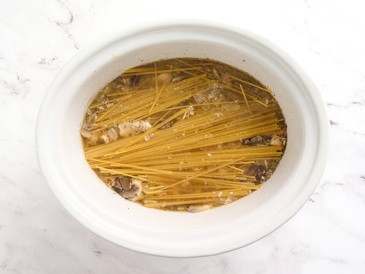 Spaghetti submerged in broth in a crockpot.