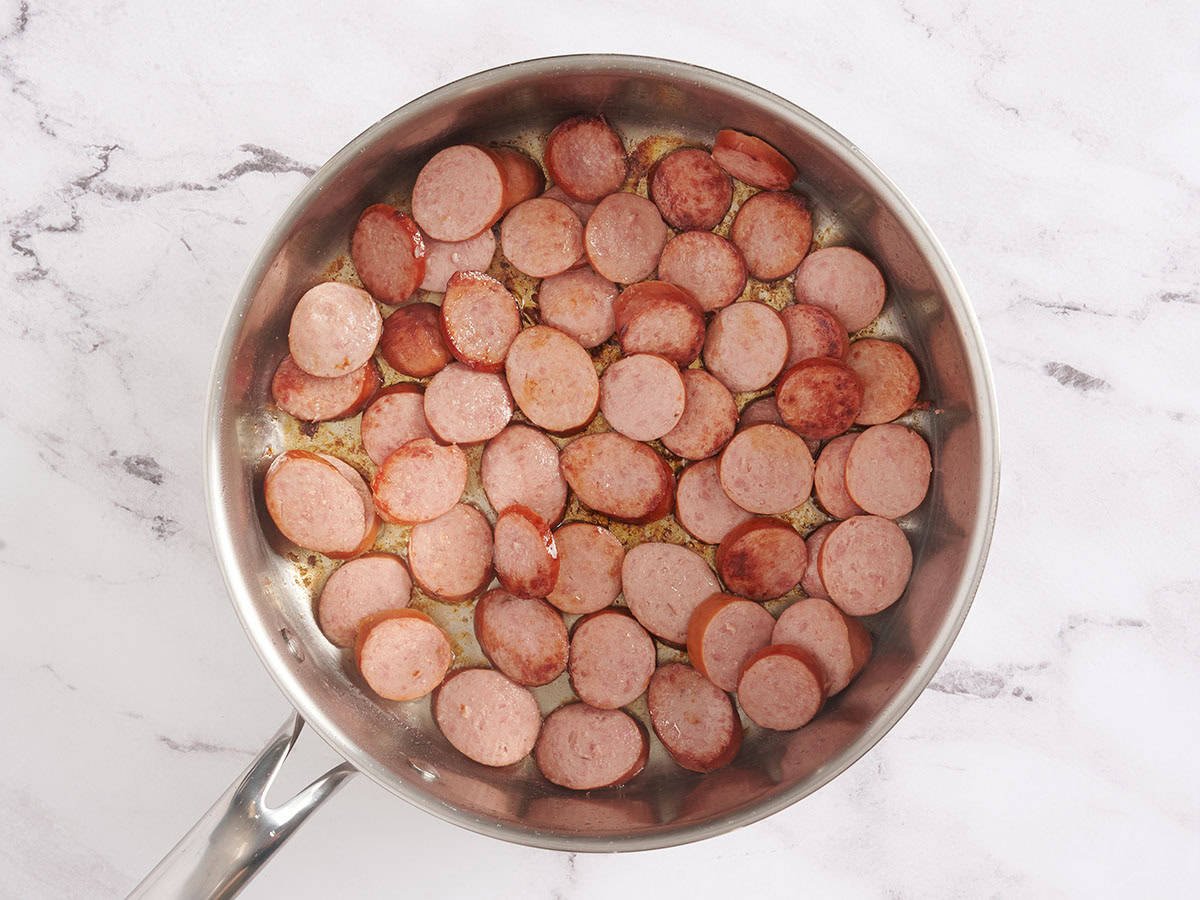 Sliced turkey sausage browning in a skillet.