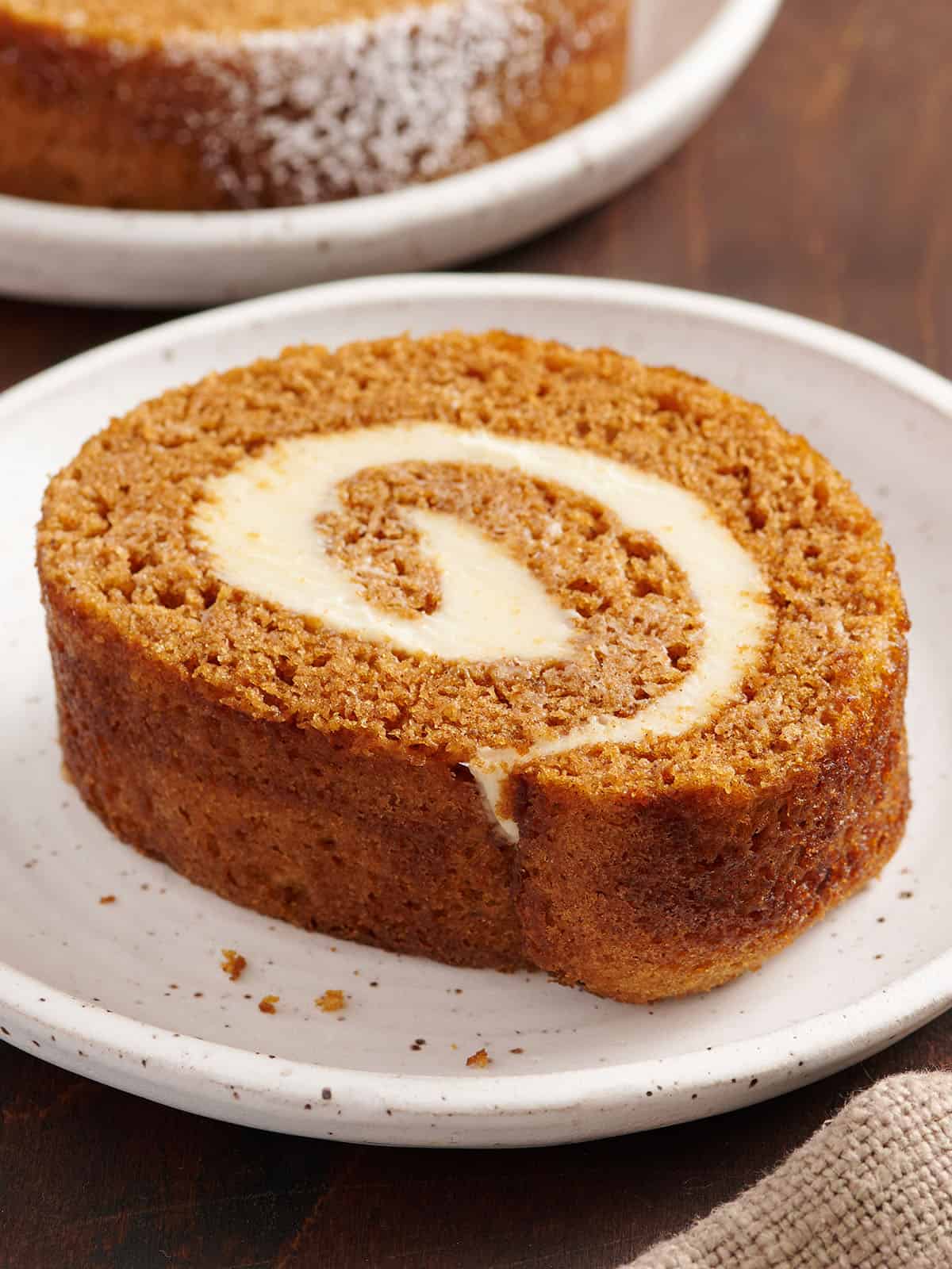 sliced pumpkin roll on a plate showing cream cheese swirl