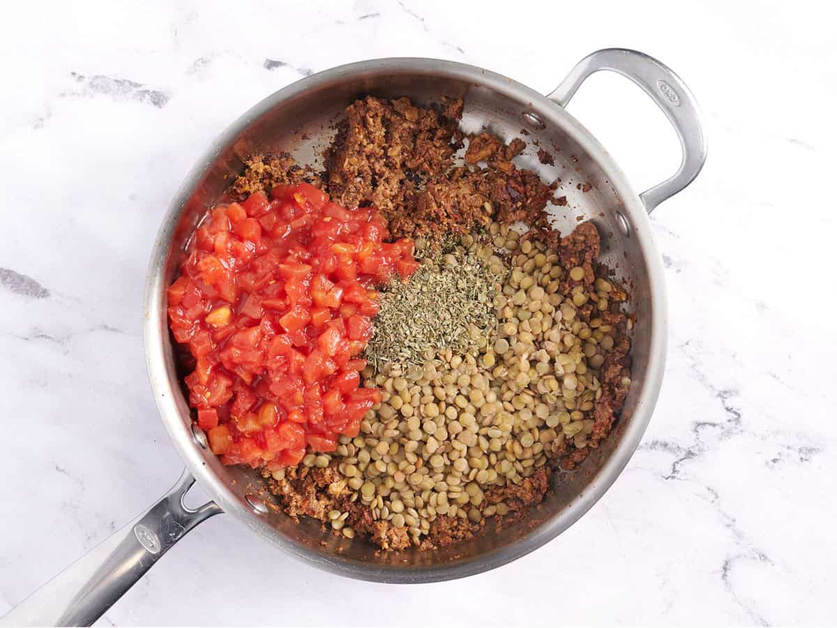 Lentils, tomatoes, and seasonings in a sauce pan.