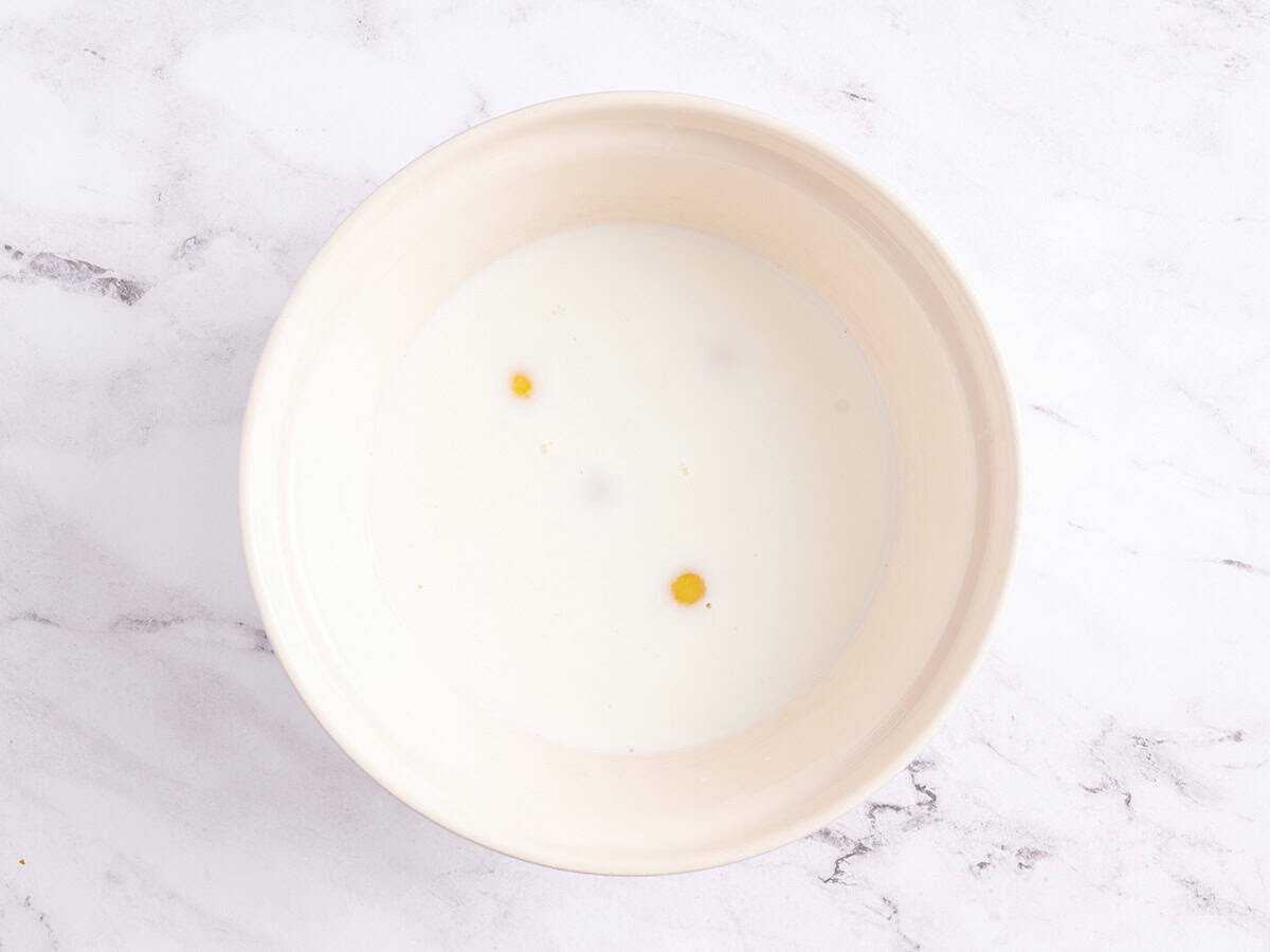 Eggs, milk, and salt in a white bowl.
