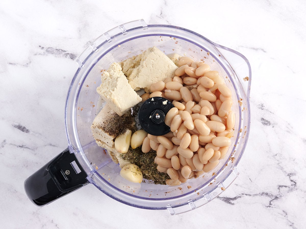 Tofu, white beans, and seasonings in a food processor.