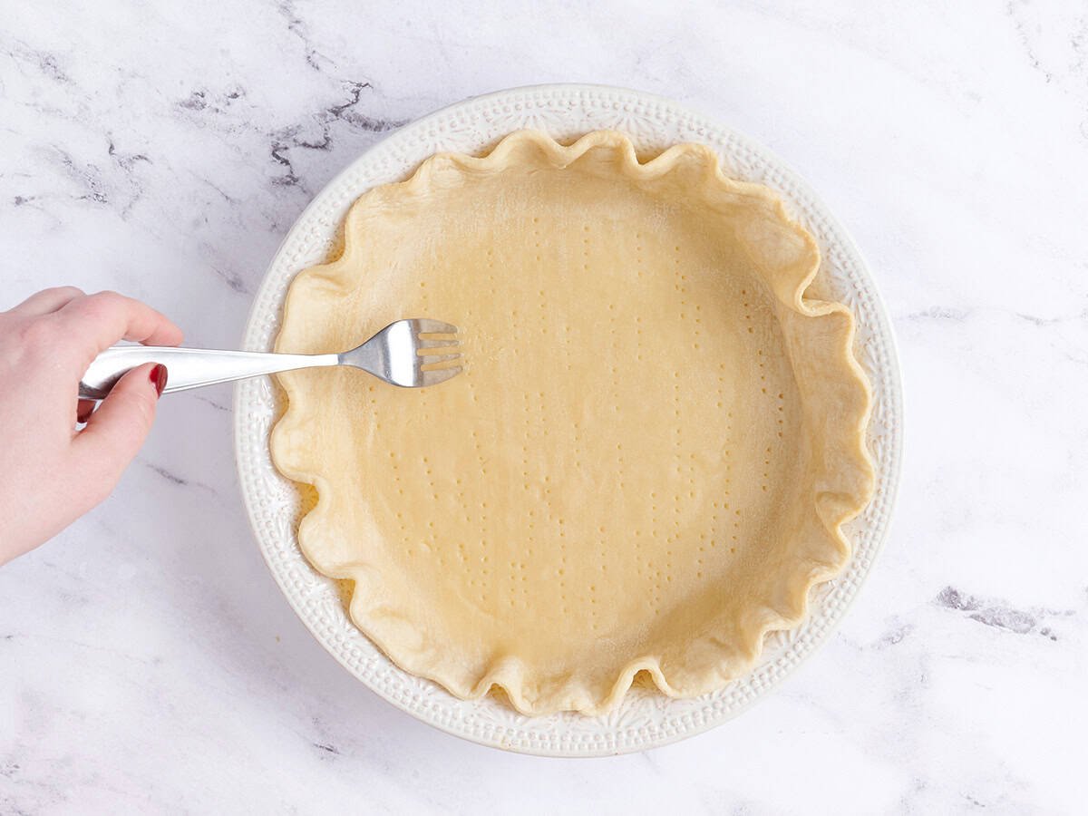A fork piercing a pie crust.