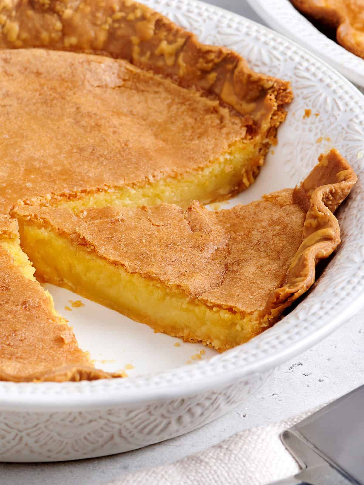 Side view of a chess pie in a pie dish with a slice missing.