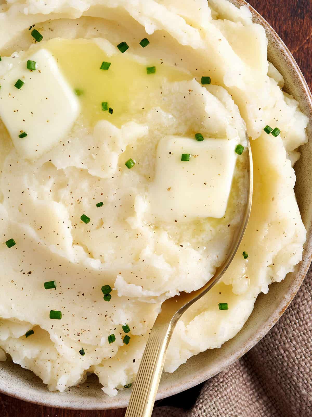 Overhead close up of buttery instant pot mashed potatoes in a bowl with a spoon.