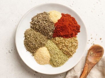 The individual spices and herbs for homemade poultry seasoning on a plate.