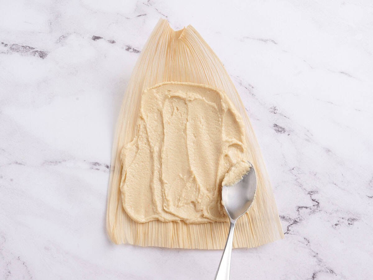 Masa harina filling spread on a corn husk.