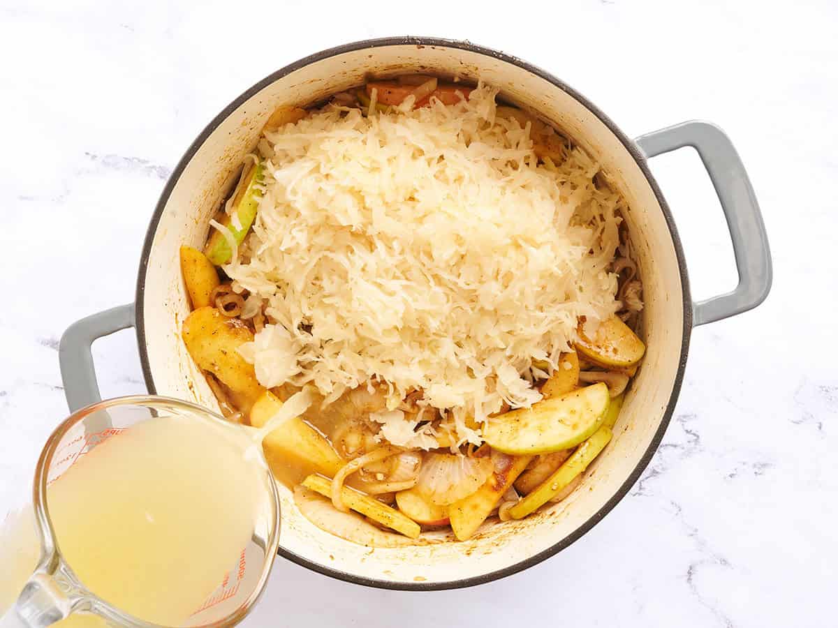 Sauerkraut and chicken broth added to a pot of sauteed apples and onions.