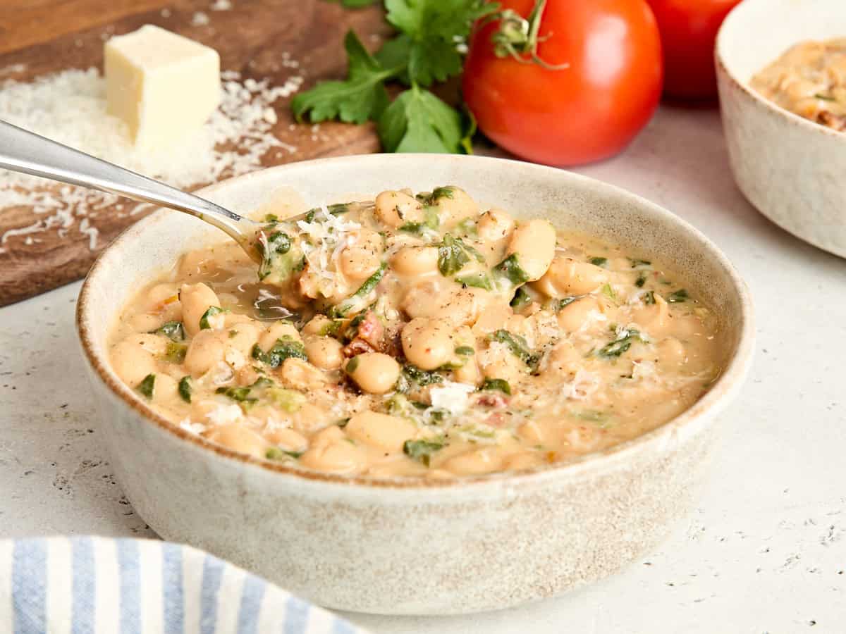 Side view of a bowl of marry me white beans with a spoon.