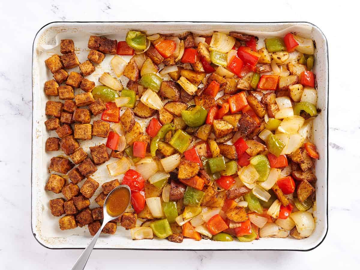 Drizzling the butter mixture over the roasted tofu and veggies.