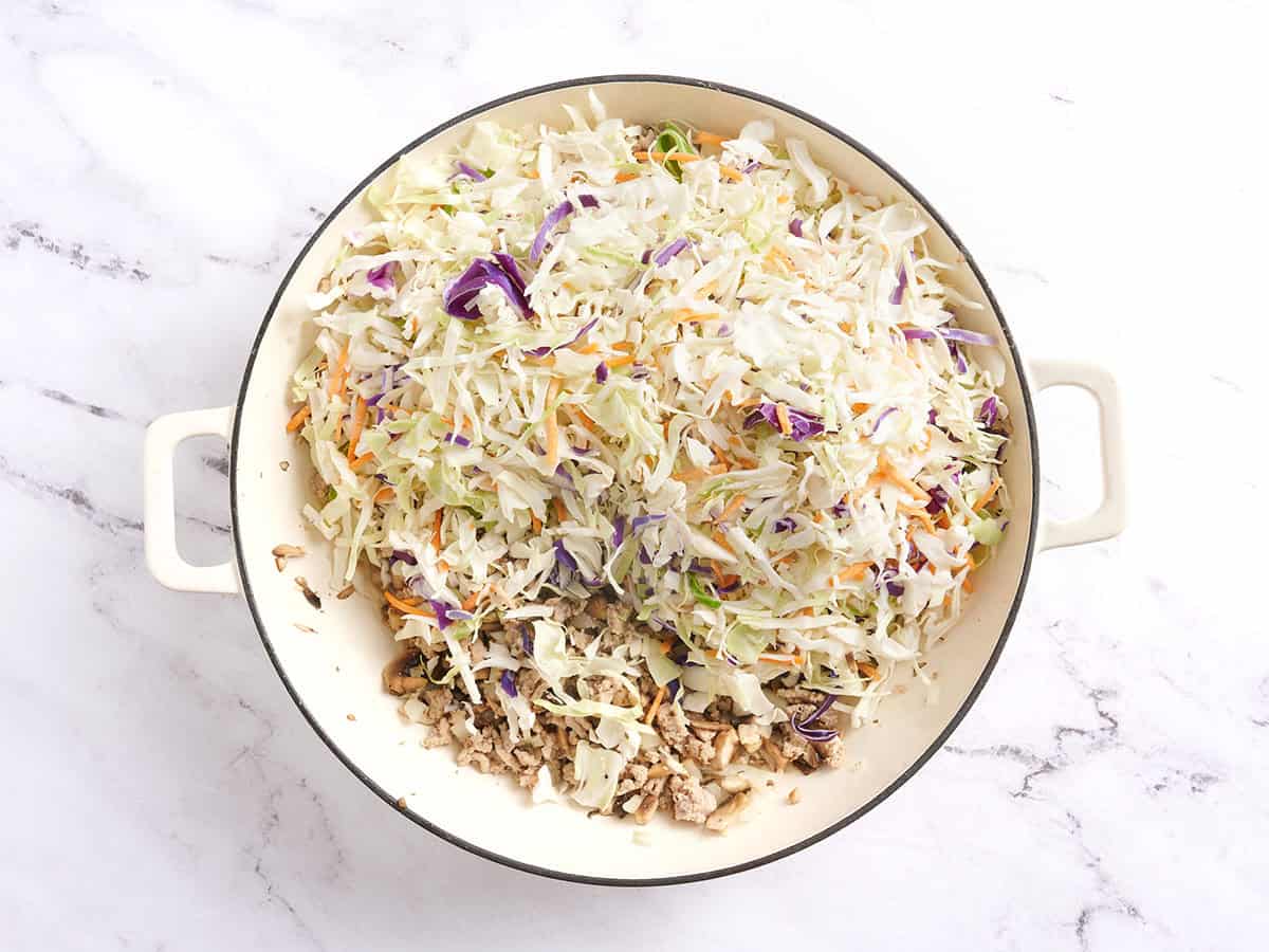 Adding the coleslaw mix to the skillet with the turkey and aromatics.