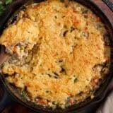 Overhead view of a homemade chicken cobbler with a spoon taking some.