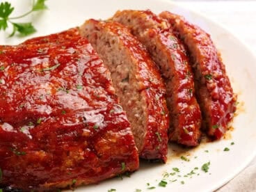 Chicken meat loaf on a platter with a few slices cut.