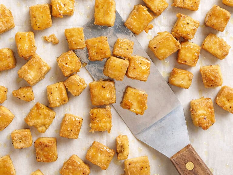 Overed view of baked tofu being scooped with a spatula.