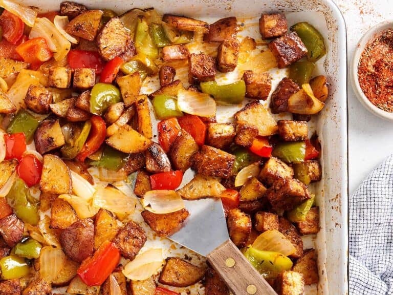 Sheet pan Cajun tofu and vegetables on a baking sheet with a spatula.