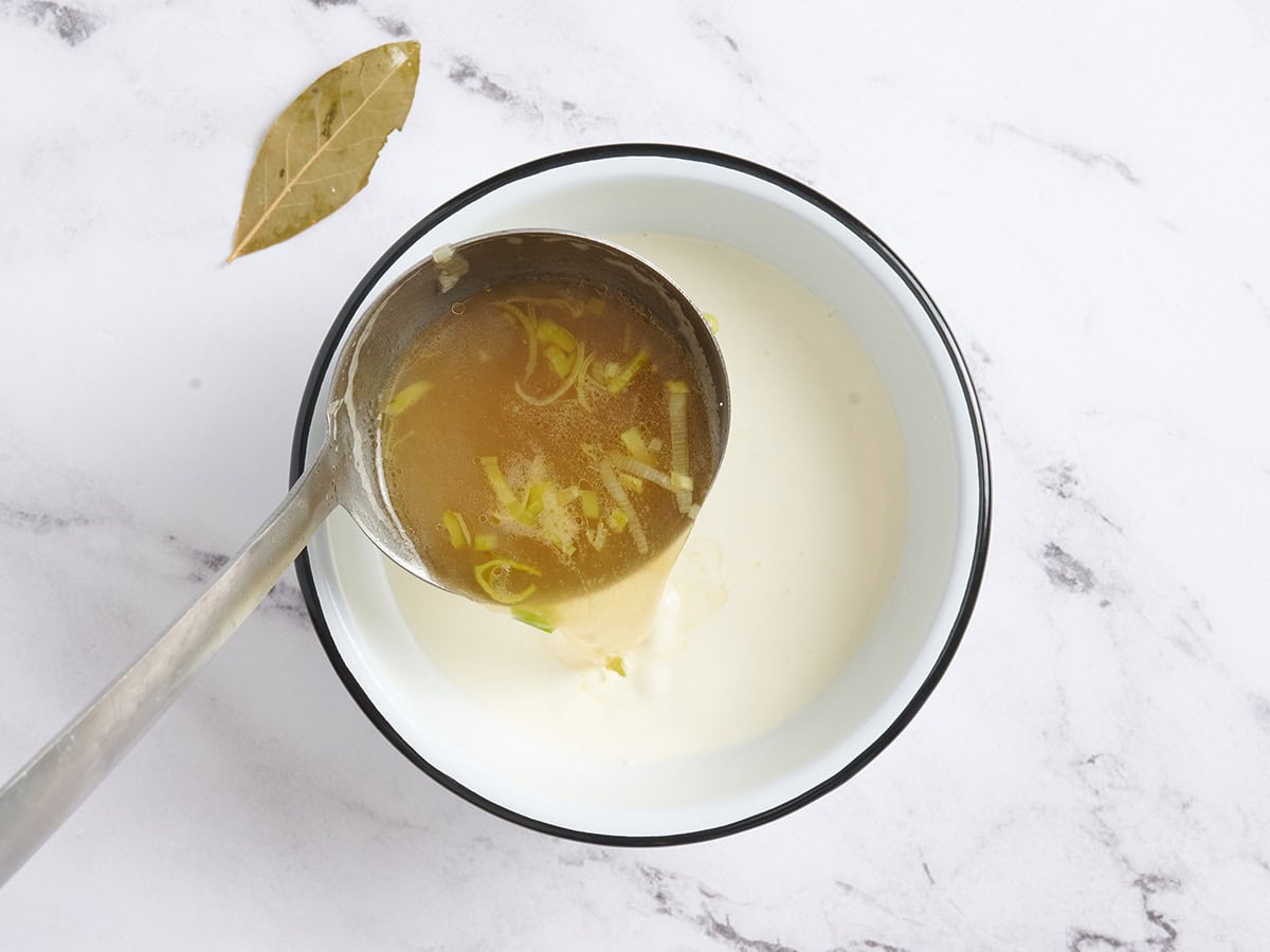 Hot soup being poured into a bowl of cream.