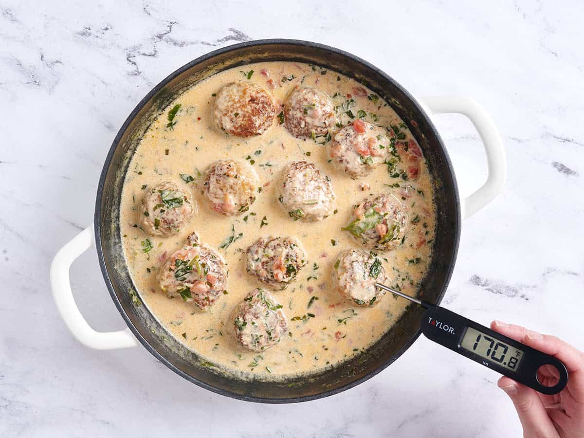 A thermometer checking the internal temperature of marry me meatballs.