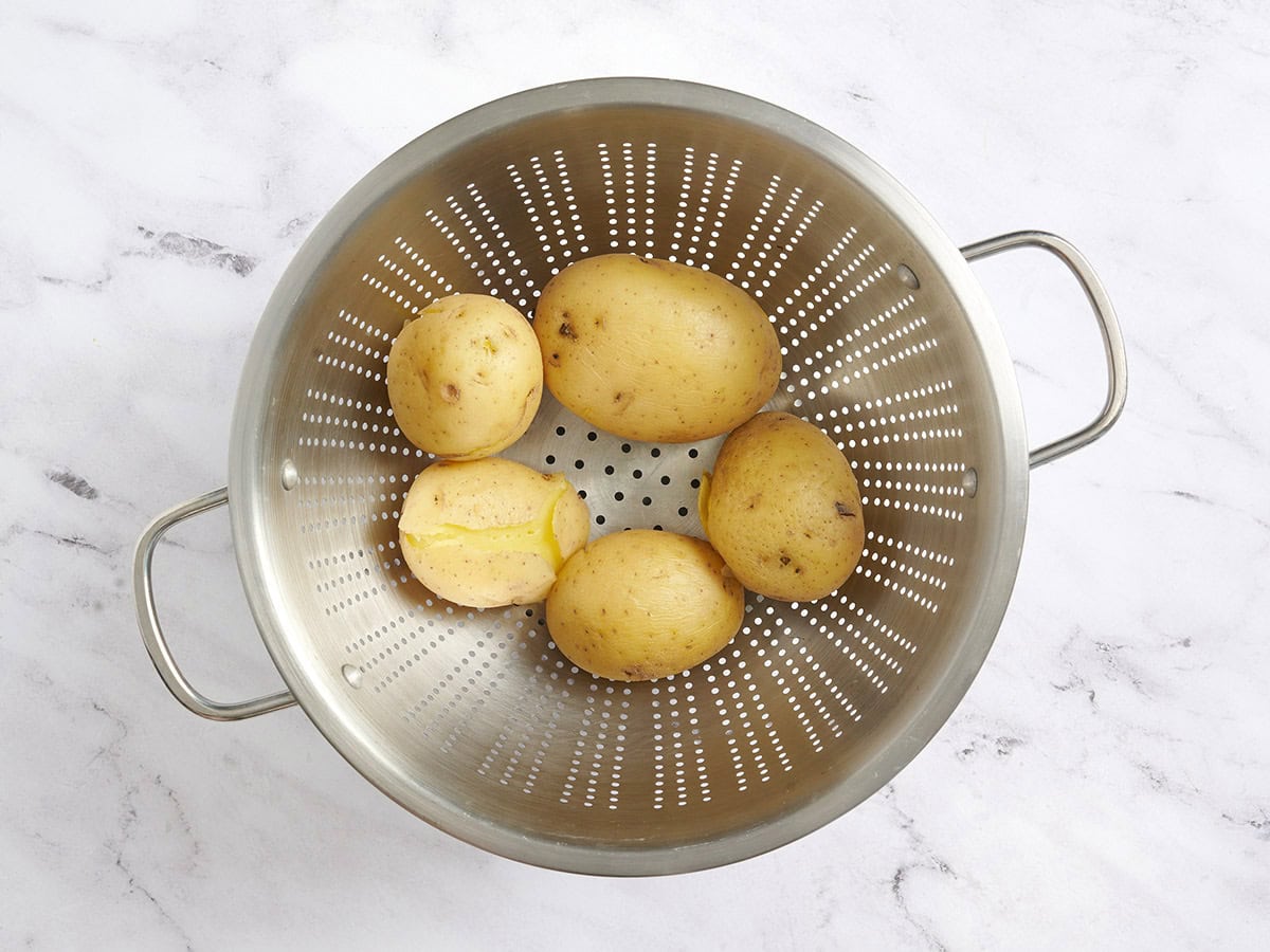 Whole boiled potatoes in a colander.