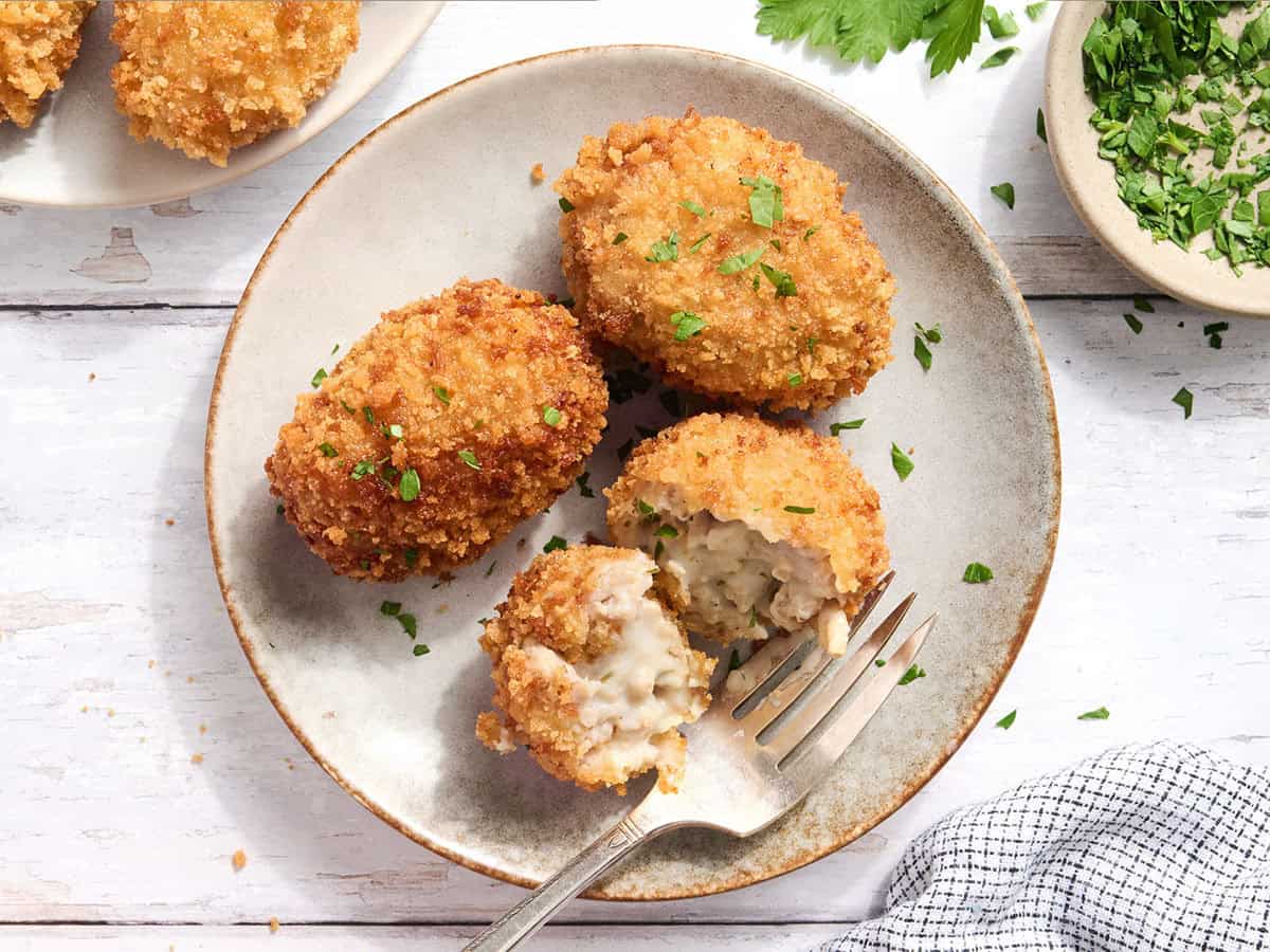Overhead view of chicken croquettes on a plate with one sliced in half.